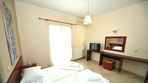 Een hotelkamer met twee bedden, een bureau, een stoel, een televisie en een spiegel.