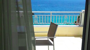 Een balkon met een stoel, een zwembad en uitzicht op de oceaan.