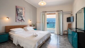 Una camera da letto con un letto, una televisione, una scrivania e vista sul mare.