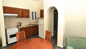 Una cucina compatta con mobili in legno, un piano cottura bianco e un tavolo con sedie.