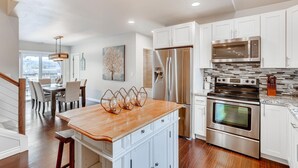 Una cocina moderna con armarios blancos, electrodomésticos de acero inoxidable y una isla de madera.