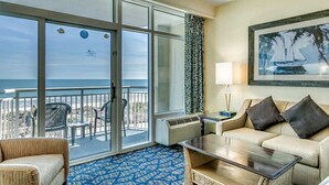 A hotel room with a balcony, a sofa, a coffee table, and a painting of a sailboat. - · Oceanfront Studio - Spectacular Views, Private Balcony! (Myrtle Beach)
