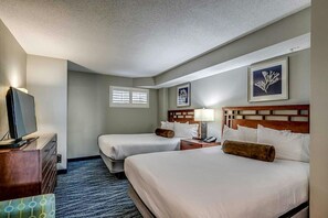 Quarto de hotel com duas camas, televisão, escrivaninha e janela.