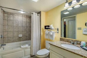 A bathroom with a bathtub, toilet, sink, and a mirror.