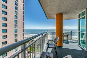 Enjoy the ocean view from this balcony with a metal railing and two comfortable chairs.