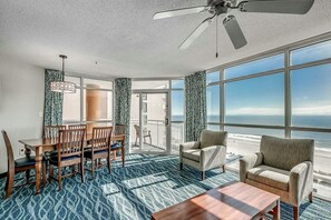Enjoy ocean views from the large window in this room, which features a dining area, sofa, and coffee table.