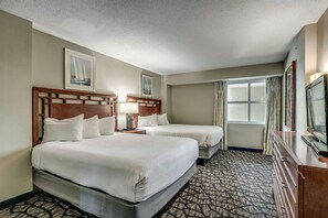 A hotel room with two beds, a television, and a patterned carpet.