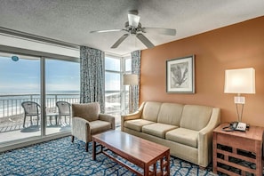 Enjoy a beach view from the comfort of this room, featuring a sofa, coffee table, and side table with a lamp.