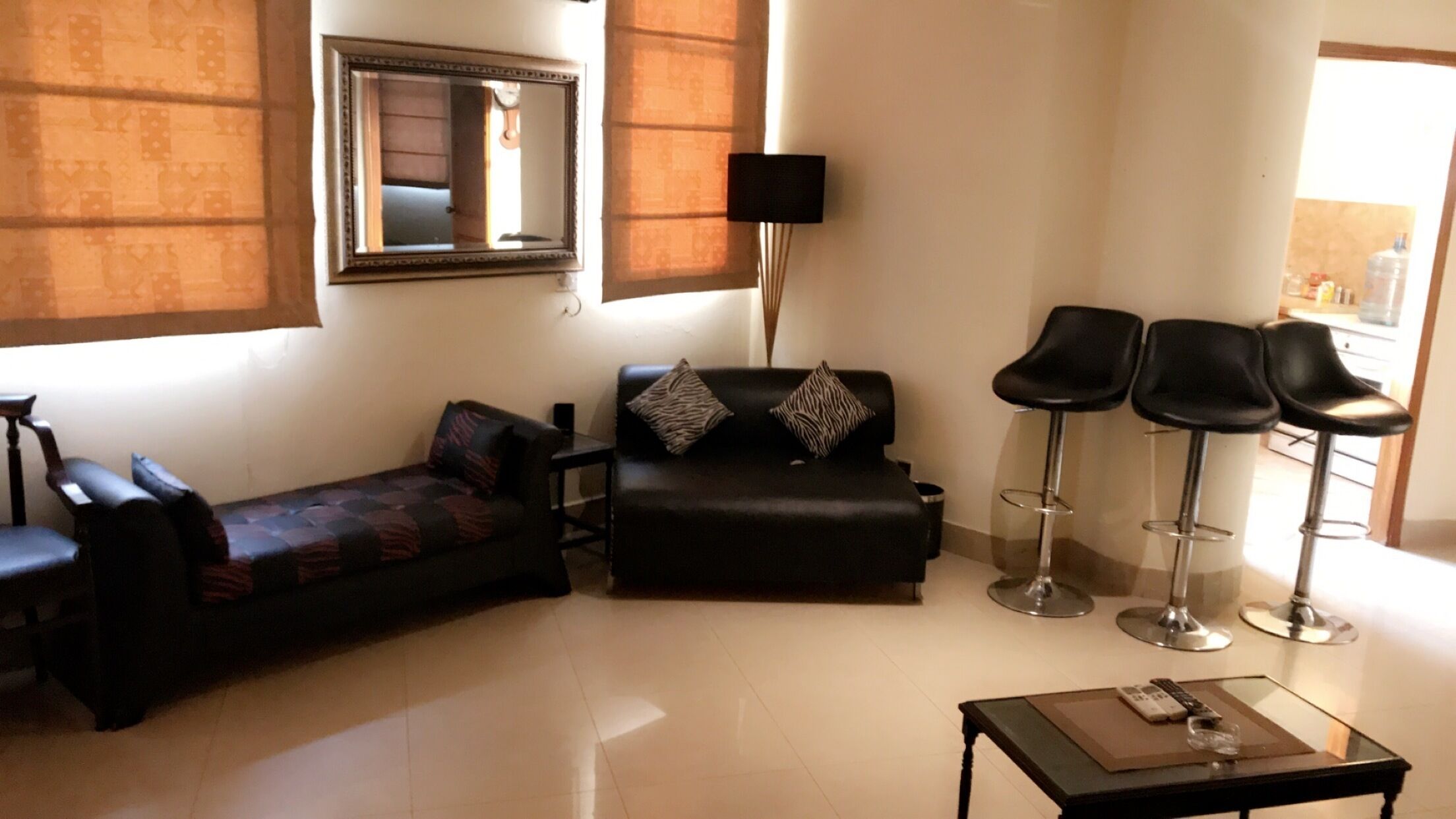 A living room with a sofa, two armchairs, a coffee table, and two bar stools.