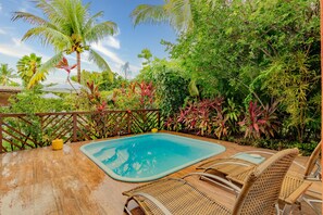 A pool area with a wooden deck, wicker lounge chairs, and lush tropical vegetation. - PF10 - Casa 3 Suítes a 300m da Praia (Mata de São João)