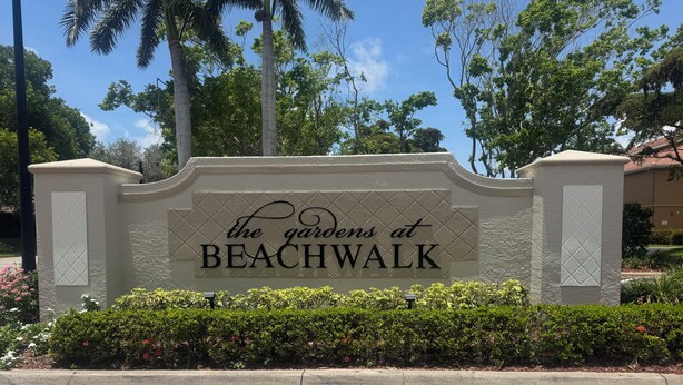 Schild für 'The Gardens at Beachwalk' mit gepflastertem Weg und Grünflächen im Vordergrund.
