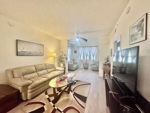 Una sala de estar con sofá, mesa de centro, televisor y un comedor con sillas y mesa.