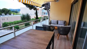 Un balcón con mesa y sillas de madera, un sofá y un toldo a rayas.