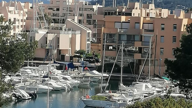 Marina con varias embarcaciones amarradas, rodeada de edificios residenciales.