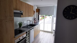 Una cocina moderna con armarios de madera, encimera negra y horno empotrado.