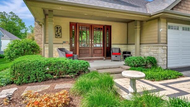 A house with a front porch, a garage, and a well-maintained garden.