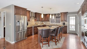 A modern kitchen with a large island, stainless steel appliances, and wooden cabinetry.