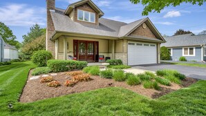 A two-story house with a garage, a front porch, and a landscaped garden.