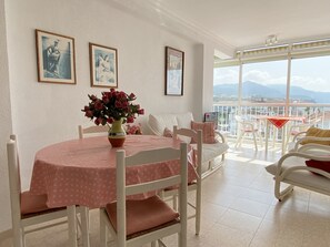 Un'area pranzo con tavolo e sedie, un vaso di fiori e un balcone con vista sulle montagne.