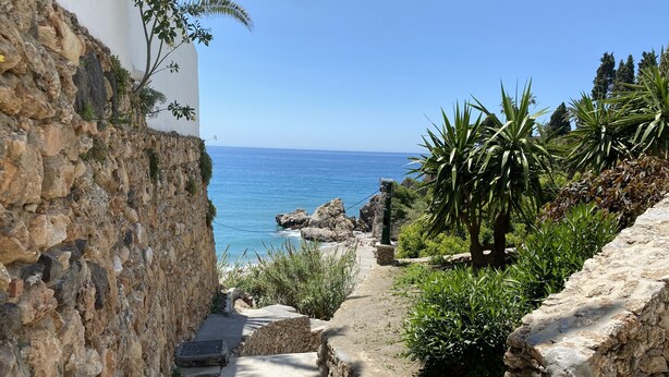 A stone staircase leading to a coastal area with a view of the sea.