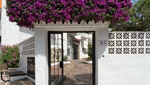 A white building with a black gate and a number '83' on the wall.