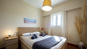 Ein ordentlich bezogenes Bett mit blauer Decke, einer Nachttischlampe und einem gerahmten Bild auf dem Nachttisch.