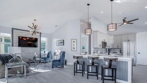 A modern kitchen with a central island, white cabinetry, and stainless steel appliances.