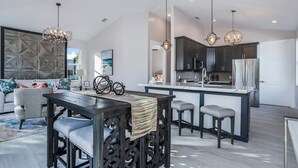 A modern kitchen with dark cabinetry, a central island, and pendant lighting.