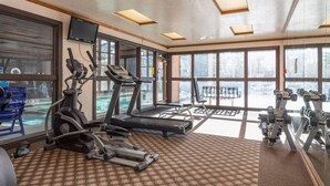 Une salle de sport équipée de tapis de course, de vélos elliptiques et de poids libres.