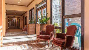 Un hall d’hôtel avec un sol à carreaux, des boiseries et des chaises rouges.