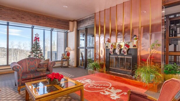 Un salon chaleureux avec une cheminée, une grande fenêtre et un sapin de Noël.