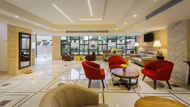 A spacious lobby with a modern design, featuring a mix of seating areas, a central coffee table, and a large mirror. - Comfort Inn Dhaliwals Gurgaon (Gurugram)