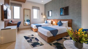A hotel room with two beds, a desk, a chair, a mirror, and a large window. - Comfort Inn Dhaliwals Gurgaon (Gurugram)