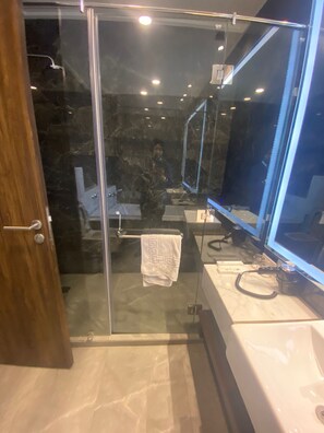 A modern bathroom with a glass shower enclosure, a marble floor, and a large mirror. - Comfort Inn Dhaliwals Gurgaon (Gurugram)