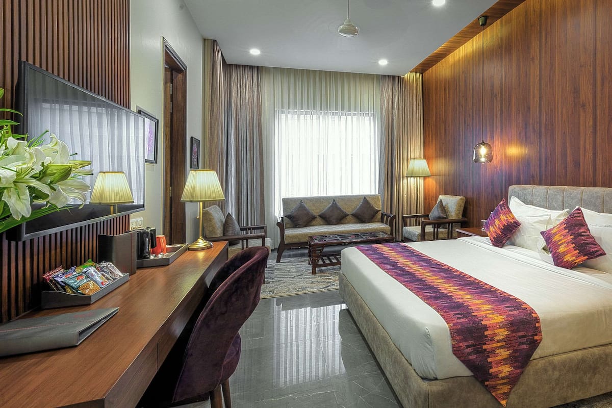 A hotel room with a bed, a desk, a sofa, and a TV.