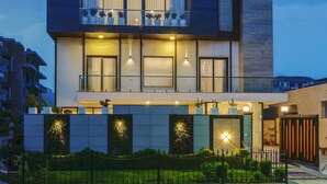A modern two-story building with a balcony, large windows, and a well-lit entrance. - Comfort Inn Dhaliwals Gurgaon (Gurugram)