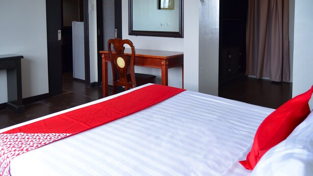 Ein Hotelzimmer mit einem ordentlich bezogenen Bett, einem Holztisch und einem Stuhl.