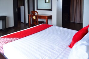 A hotel room with a neatly made bed, a wooden desk, and a chair. - OYO 791 Bell Mansion (Quezon City)