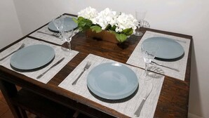 A dining table set with plates, cutlery, and a vase of white flowers.