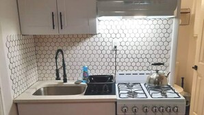 A compact kitchen with white cabinets, a stainless steel sink, a gas stove, and a built-in oven.