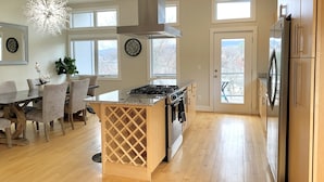 Een moderne keuken met een centraal eiland, roestvrijstalen apparatuur en grote ramen.