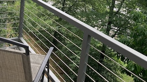 Een balkon met metalen hekwerk met uitzicht op een weelderig groen landschap.