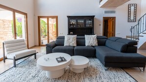 Ein modernes Wohnzimmer mit einer Eckcouch, zwei runden Couchtischen und einer dunklen Holzkommode.