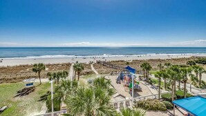 A beach view with a playground and palm trees. - · Oceanfront Deluxe King. Indoor Waterpark, Pools and More (Myrtle Beach)