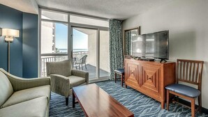 A hotel room with a balcony, a flat-screen TV, a wooden cabinet, and a sofa. - · Oceanfront King Suite - Multiple Pools, Indoor Waterpark and More (Myrtle Beach)