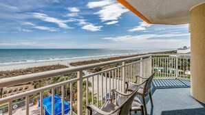 A balcony with a view of the beach and ocean.