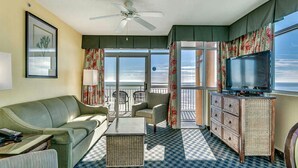 Ein Hotelzimmer mit Balkon, einer Couch, einem Couchtisch, einem Fernseher und einem Korbuscheinmöbel.