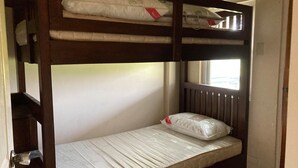 Ein Stockbett mit Matratzen und Kissen, ein Fenster und eine Tür.