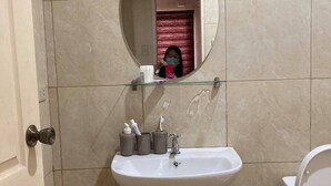 Ein Badezimmer mit einem weißen Waschbecken, einem Spiegel und einer Toilette.