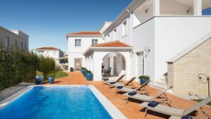 A poolside area with a clear blue pool, lounge chairs, and potted plants. - Villa Palazzo di Cleo with Pool (Vabriga)